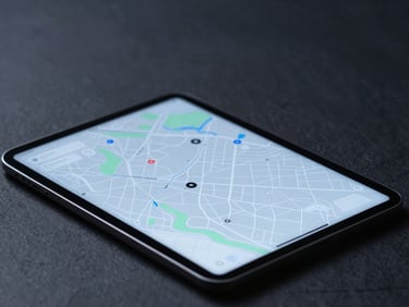 Minimalist tech photography, cool diffused studio lighting, dark slate and electric blue tones, macro depth of field showing a clean map-based UI on a tablet.