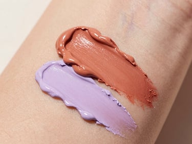 Macro close-up of creamy terracotta and soft lilac makeup smears on unretouched skin, warm natural daylight, 35mm lens