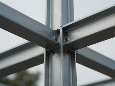 Extreme macro crop of brushed metal structural framing, high-contrast overcast daylight.
