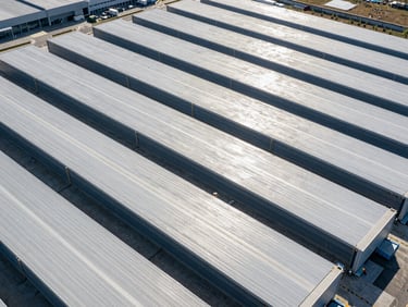 Aerial pattern of a modern logistics and distribution center, clean organized lines, high-contrast lighting.