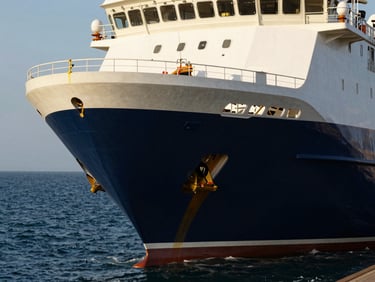 High-tech maritime vessel hull close-up in crisp coastal daylight, deep navy water, sharp architectural focus.