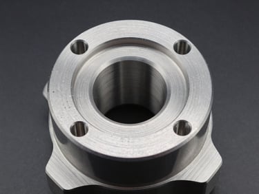 Close-up studio photograph of a precision-machined automobile component, turned aluminium surface with visible tool paths and tight bore tolerances, strobe-lit against a neutral dark background, macro framing isolating the machined geometry