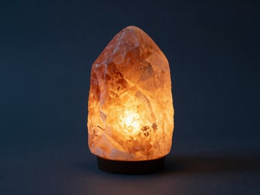 Glowing Himalayan salt lamp in a minimalist interior, warm internal illumination, soft shadows, deep slate and warm amber tones, 35mm lens