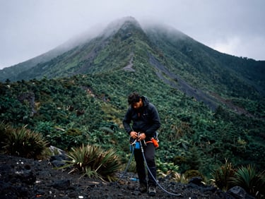 Andean mountain guide adjusting gear, misty volcanic landscape in background, cool overcast skies, high contrast, 35mm