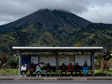 A public transport stop in Ecuador with passengers waiting under a cool overcast sky, high contrast, 35mm