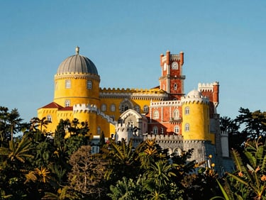 The fairy-tale Pena Palace in Sintra surrounded by lush green forests, bright yellow and terracotta towers under a clear blue sky.