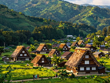 Historic thatched-roof farmhouses of Shirakawa-go nestled in a lush green valley, dramatic mountain backdrop, golden hour light.
