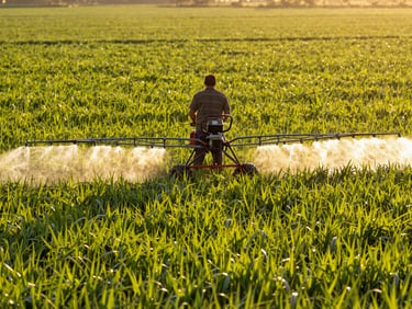 Farmer operating a modern sprayer in a lush green field, water mist, golden-hour sunlight, 35mm