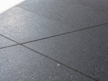 Extreme macro technical photography of installed dark gray textured ceramic tile flooring in a busy modern transit terminal, sharp natural light