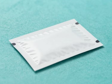 Clean clinical photography of a modern medicine package on a sterile teal surface, bright high-key studio lighting, sharp focus, 50mm