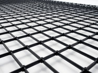 Extreme close-up of a black biaxial geogrid, highlighting the rigid rib junctions and square aperture structure, clean industrial studio lighting.
