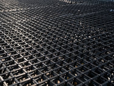 Close-up of a black high-tensile geogrid structure, highlighting the rigid polymer grid junctions, technical studio lighting.