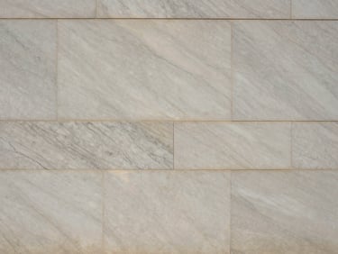 Straight-on architectural elevation of a finished marble wall, showcasing continuous vein alignment across multiple panels under natural raking light.