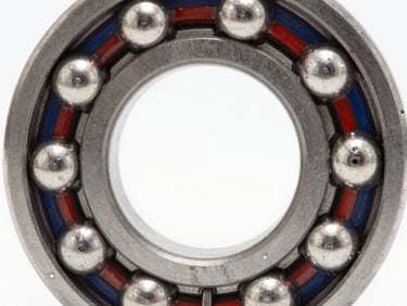 Macro shot of a high-precision industrial ball bearing, polished steel texture, sharp reflections, high-key studio lighting.