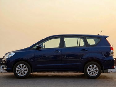Side profile of a polished dark blue Toyota Innova Crysta parked on a quiet street in Vrindavan, dusk lighting