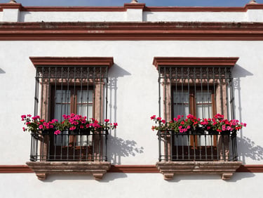 Fachada de casa colonial en el centro histórico de Oaxaca, con balcón de hierro forjado y buganvilias, luz natural brillante, tomas arquitectónicas rectas.