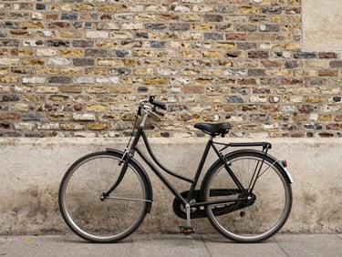 A classic vintage city bicycle leaning against a textured brick wall in Nantes, soft morning daylight, realistic lifestyle photography