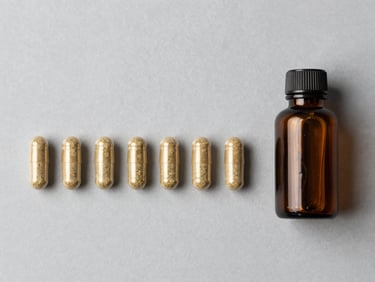 Flat-lay overhead of finished herbal supplement capsules arranged in a row beside a small labeled amber glass bottle on a neutral grey surface, bright even studio lighting