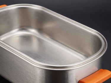Close-up of a large, gleaming stainless steel electric roaster in operation, sharp rim lighting, dark moody background, orange accents, 50mm.
