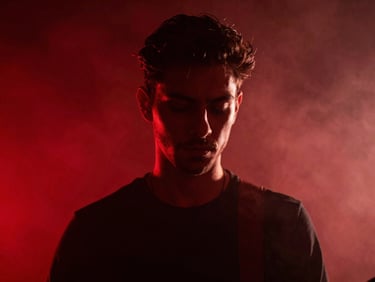 Cinematic portrait of a musician in deep focus, dramatic red neon backlight, smoky background, high contrast shadow, anamorphic crop