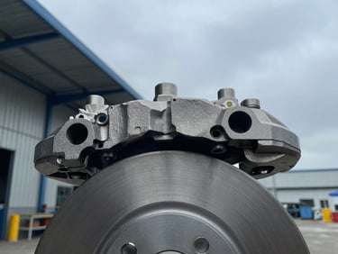 Close-up of high-precision steel automotive brake caliper, cool overcast warehouse lighting, sharp metal details