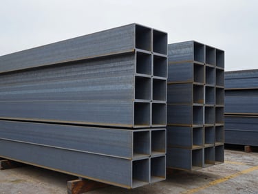 Stacked raw industrial steel beams and aluminum profiles in a shipping yard, cool overcast daylight, high contrast