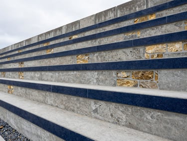 Sharp architectural photography of a multi-tiered concrete block retaining wall on a steep Bellevue hillside, precise alignment, built-in gravel drainage trench, bright overcast daylight, 24mm.