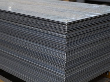 Close-up of a stack of very thick steel plates, cool clean workshop light, desaturated steel and navy tones, deep depth of field.
