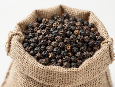 Bright macro shot of raw whole black peppercorns in a bulk burlap sack, clean warehouse setting, sharp focus