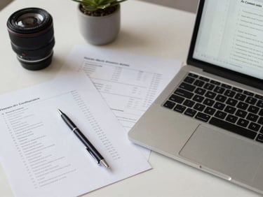 Overhead shot of a workspace desk with printed product listing drafts, a laptop open to an Amazon A+ content editor, bright flat office lighting, pen resting on annotated copy