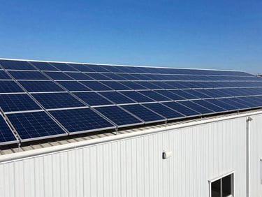 Industrial warehouse roof with a massive 500kW solar array, high-contrast architectural photography, deep blue skies.
