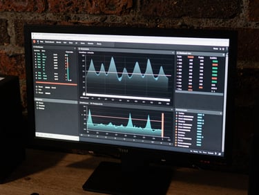 Overhead shot of a clean digital dashboard on a monitor in a dark brick office, showing high-contrast analytics graphs, desaturated tones, 35mm film.