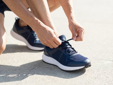 Close-up of hands lacing up running shoes at dawn, crisp shadows, natural light, focused action, crisp editorial photography, bright morning daylight, high-contrast natural tones, clean modern composition, 35mm lens
