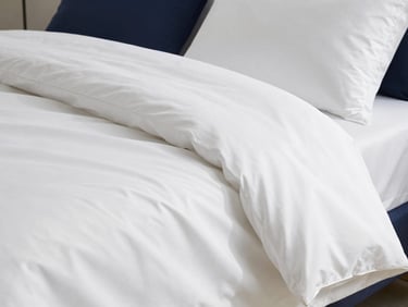 Crisp white sateen bed linen draped smoothly, showing subtle sheen, bright natural daylight, minimal styling.