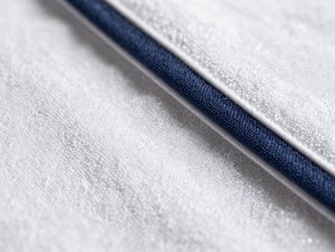 Macro shot of a tightly woven, soft white bath towel texture, bright natural daylight, sharp detail.
