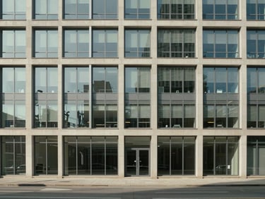 Wide-angle view of an office building facade at midday, windows evenly spaced and perfectly clean, neutral daylight, no reflections, empty street below, systematic grid of glass panes