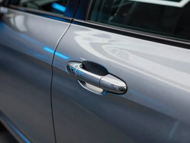 Close-up of a perfectly polished metallic car door showing a sharp, mirror-like reflection of neon blue workshop lights