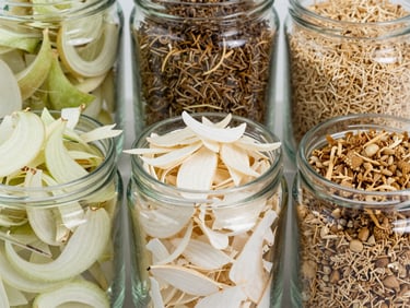 Crisp commercial photography of dehydrated white onion flakes and garlic granules in clean glass containers, bright natural daylight, clean agricultural styling, 35mm lens