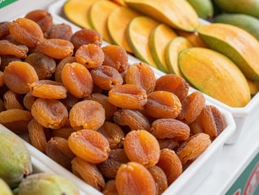 Crisp commercial photography of premium dried apricots and sliced mangoes in a clean wholesale display, bright natural daylight, rich orange and golden tones, 35mm lens