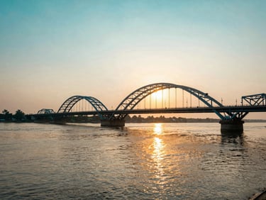 Wide panoramic shot of the historic Godavari Arch Bridge in Rajahmundry at sunset, golden light reflecting on the wide river water, 35mm photography