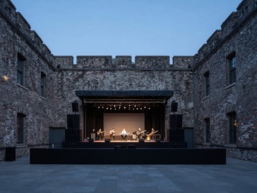 Crisp eye-level photo of an outdoor courtyard concert during blue hour, subtle stage lighting, historical brick walls, desaturated tones.