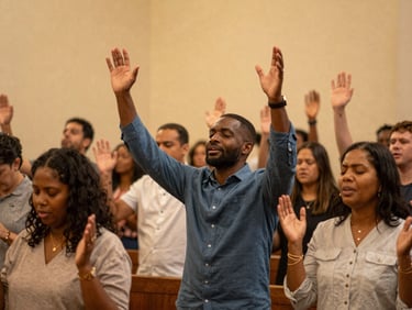 A diverse congregation raising hands in passionate worship under warm, golden sanctuary light, authentic 35mm photography