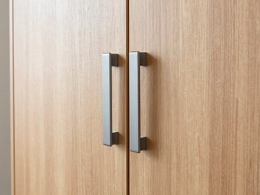 Straight-on elevation of a minimalist walnut wood wardrobe with integrated matte grey handles, bright natural daylight