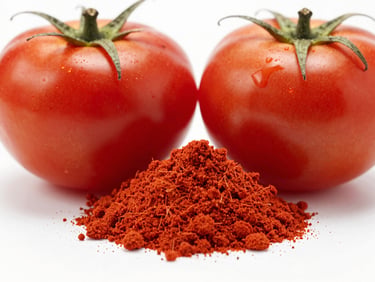 Macro studio shot of vibrant red tomato powder next to fresh ripe tomatoes, bright high-key lighting, sharp focus.