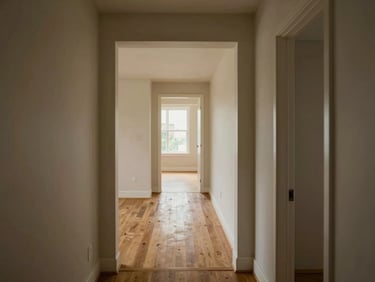 Wide-angle view from a hallway looking through consecutive rooms of an unfurnished townhouse, natural daylight entering from windows at the far end, architectural doorframes creating depth and framing, warm hardwood floors throughout