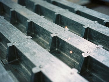 Industrial film photography of custom-cut steel gusset plates and heavy brackets, cool steel tones, sharp focus, 35mm.