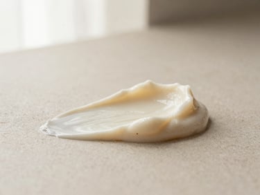 Editorial macro shot of rich creamy body scrub texture on a neutral stone surface, soft morning light, warm cream tones, shallow depth of field, 35mm