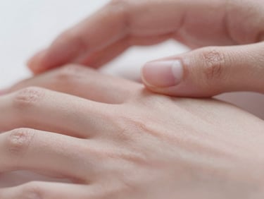 Macro close-up of soft glowing skin, gentle touch of hands, warm diffused daylight, muted dusty rose tones, shallow depth of field
