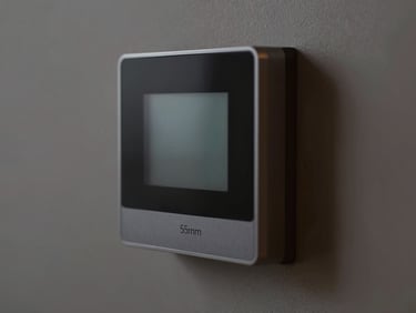 Macro shot of a modern, minimalist smart thermostat integrated flush into a wall, showing a subtle temperature display, clean interior lighting, deep charcoal and amber tones, high detail, 35mm