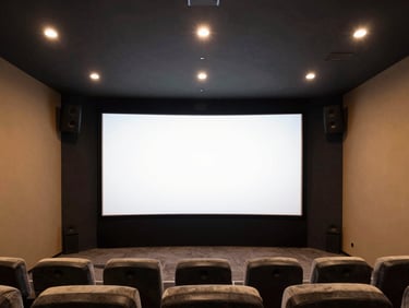 Straight-on architectural shot of a modern home theater with invisible speakers and a large screen, clean interior lighting, deep charcoal and amber tones, high detail, 35mm.